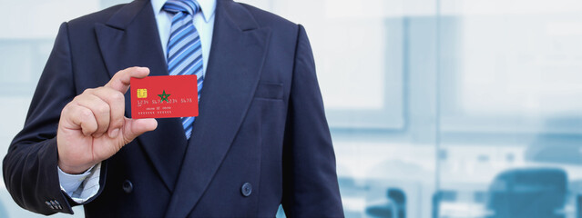 Cropped image of businessman holding plastic credit card with printed flag of Morocco. Background...