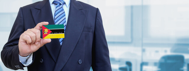 Cropped image of businessman holding plastic credit card with printed flag of Mozambique....