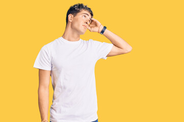 Young handsome man wearing casual white tshirt confuse and wondering about question. uncertain with doubt, thinking with hand on head. pensive concept.