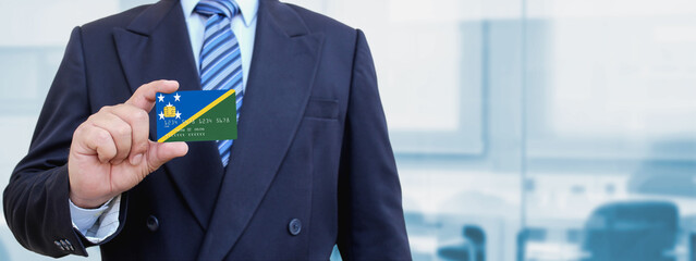 Cropped image of businessman holding plastic credit card with printed flag of Solomon Islands....