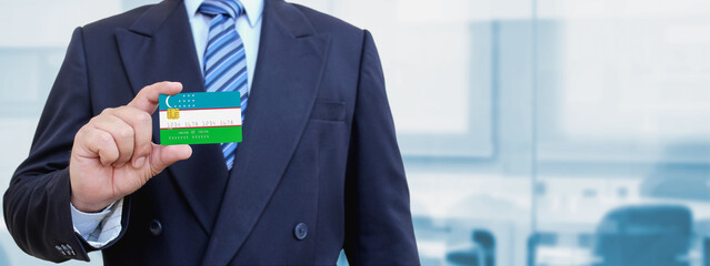 Cropped image of businessman holding plastic credit card with printed flag of Uzbekistan....