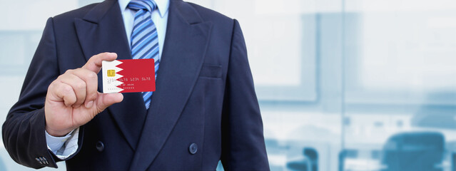 Cropped image of businessman holding plastic credit card with printed flag of Bahrain. Background...