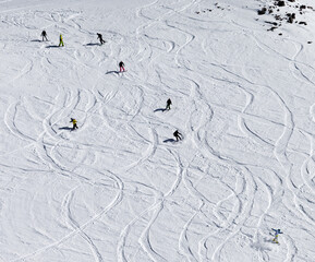 Snowboarders and skiers downhill on off piste slope.