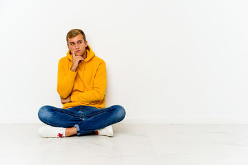 Young caucasian man sitting on the floor contemplating, planning a strategy, thinking about the way of a business.