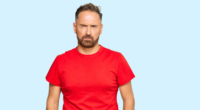 Handsome middle age man wearing casual red tshirt skeptic and nervous, frowning upset because of problem. negative person.