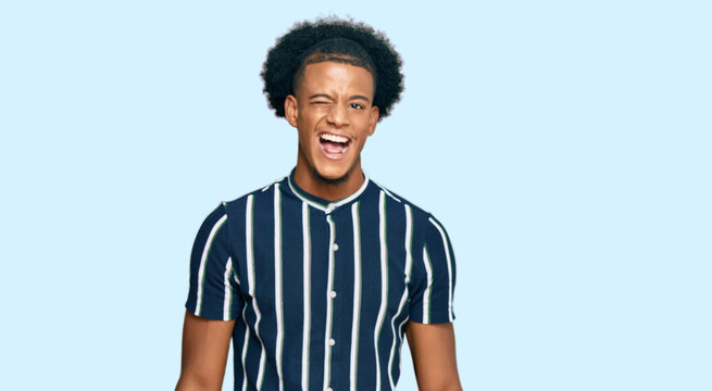 African american man with afro hair wearing casual clothes winking looking at the camera with sexy expression, cheerful and happy face.
