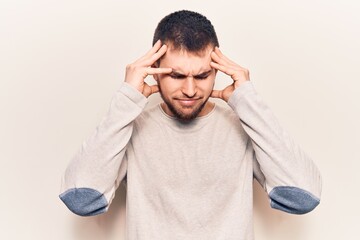 Naklejka premium Young handsome man wearing casual sweater suffering from headache desperate and stressed because pain and migraine. hands on head.