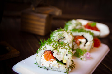 Green maki sushi. Roll made of smoked salmon, cream cheese and cucumber inside. Dill outside