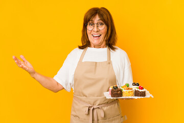 Middle age caucasian cook woman receiving a pleasant surprise, excited and raising hands.