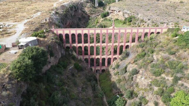 Scenic aerial view of Aqueduct of Eagle, four storied arch bridge over canyon of Barranco de la Coladilla on sunny fall day, Nerja, Spain
