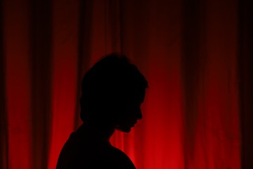 Obraz premium silhouette of a person in a red curtain-conceptual photography of migraine, headache , anxiety, depression and frustration 