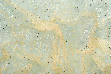 Wrinkled airy fabric with gold glitter on light blue background. Abstract, chic flat lay.