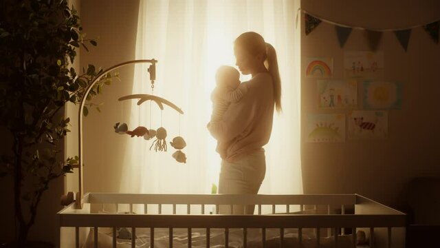 Genuine Footage of Happy Mother Holding a Cute Newborn Baby in Cozy Warm Kids Bedroom. Caring Mom and Neonate Toddler are Bonding at Home. Concept of Childhood, New Llife, Parenthood.
