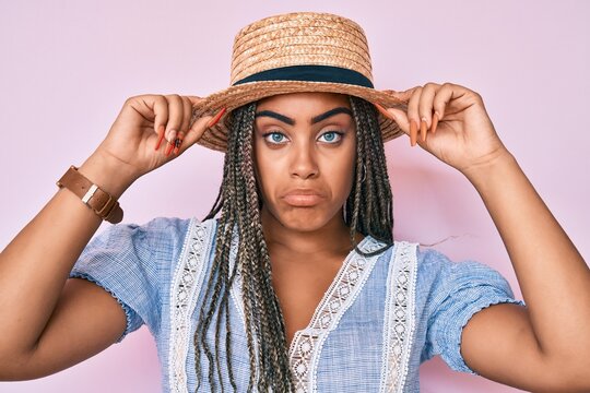 Young african american woman with braids wearing summer hat depressed and worry for distress, crying angry and afraid. sad expression.