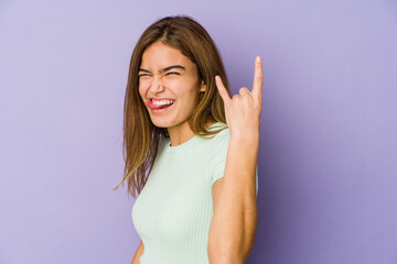 Fototapeta na wymiar Young skinny caucasian girl teenager on purple background showing rock gesture with fingers