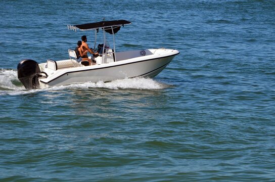 Young couple cruising on the Florida Intra-Coastal Waterway in a small open white sport fishing boat.