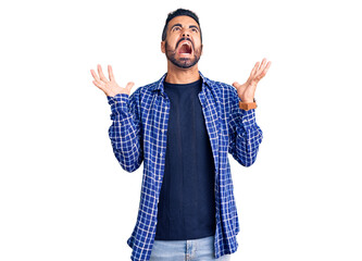Young hispanic man wearing casual clothes crazy and mad shouting and yelling with aggressive...