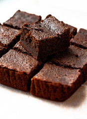 Homemade tasty chocolate brownie pieces on a white table. Side view. Vertical orientation