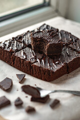 Brownie pieces. A bited piece of homemade tasty chocolate brownie cake with a spoon of melted chocolate. Side view. Vertical orientation