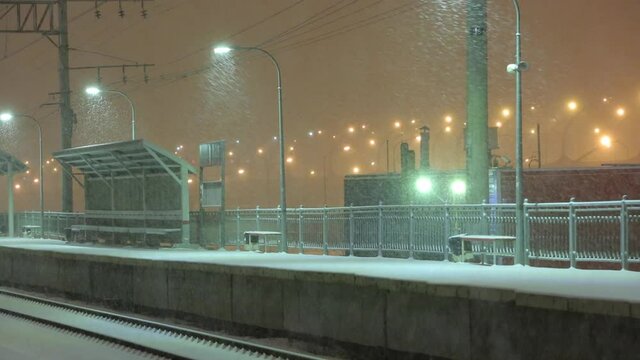 Empty railway platform without passengers in blizzard or heavy snowfall at night. Railway, bad weather, winter season concept