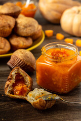 Pumpkin jam. Tasty homemade sweet spicy vegetable jam in a glass jar. Profiteroles and pumpkins background. Vertical orientation