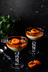 Tasty italian dessert panna cotta with apricot jam layer with green plant background. Low key....