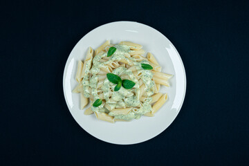 Pesto penne pasta dish on a black background