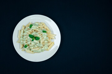 Pesto penne pasta dish on a black background