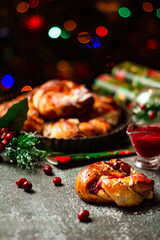 Tasty homemade braided buns with cranberry jam. Christmas and New Year decorations. Bokeh lights background. Vertical orientation