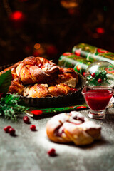 Tasty homemade braided buns with cranberry jam and sugar powder. Christmas and New Year decorations. Bokeh lights background. Vertical orientation