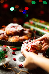 Tasty homemade braided bun with cranberry jam and sugar powder. Christmas and New Year decorations. Bokeh lights background. Vertical orientation