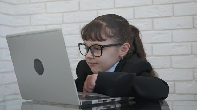 Child in computer business. A concentrated child win in computer and with big happy smiling eyes look at the screen.