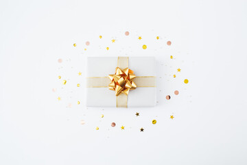 Christmas present and gift and golden confetti on white background. Merry christmas, New Year holiday concept. Flat lay, top view, copy space.