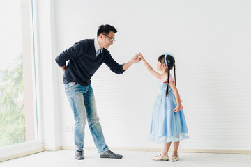 An Asian father and daughter are dancing, dad teaches daughters to dance in a fun room