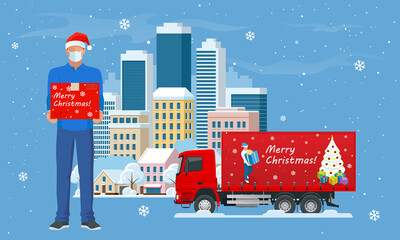 Delivery trucks delivering Christmas gift and Courier in a face mask and a Christmas hat with a box in his hands in the city and snow falling. Delivering by to home. Gifts in bright boxes Winter city.
