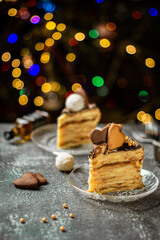 Napoleon cake pieces. Tasty homemade layer cake from puff pastry with custard vanilla cream and heart cookies on the top. Christmas, New Year and Valentine decorations. Bokeh lights background.