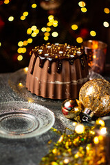 Tasty Three Chocolates mousse cake with ganache in Christmas and New Year decorations. Chocolate cake with layers. Bokeh lights background. Vertical orientation. Christmas Eve. Low Key.
