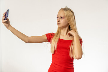 Teenage girl with blond hair in red dress holds phone
