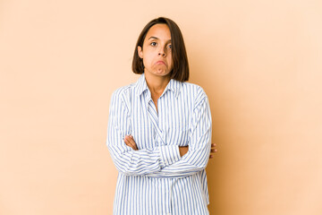 Young hispanic woman isolated shrugs shoulders and open eyes confused.