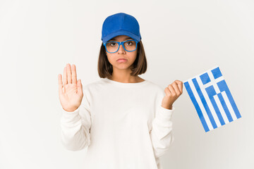 Young hispanic mixed race woman holding a greece flag standing with outstretched hand showing stop sign, preventing you.