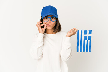 Young hispanic mixed race woman holding a greece flag with fingers on lips keeping a secret.