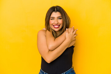 Young indian woman isolated on yellow background hugs, smiling carefree and happy.