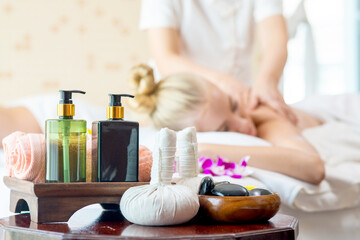 Beauty Spa and body massage equipment with aroma essential oil skincare and herbal ball on the table in beauty salon with beautiful woman lying on spa bed get back massage treatment background.