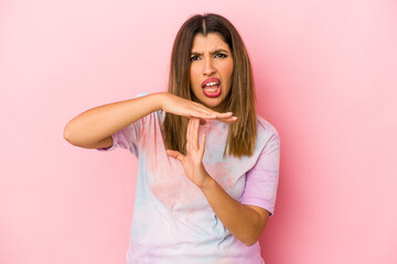 Young indian woman isolated on pink background showing a timeout gesture.