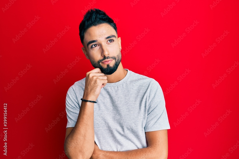 Canvas Prints Young man with beard wearing casual white tshirt thinking concentrated about doubt with finger on chin and looking up wondering