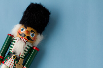 Interesting beautiful christmas nutcracker soldier on blue colored paper surface texture with copy...