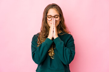 Young caucasian woman holding hands in pray near mouth, feels confident.