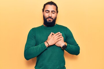 Young arab man wearing casual clothes smiling with hands on chest, eyes closed with grateful gesture on face. health concept.