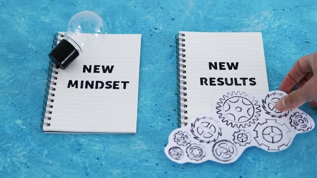 law of attraction, notepad with New Mindset New Results text with light bulb and gearwheel mechanism
