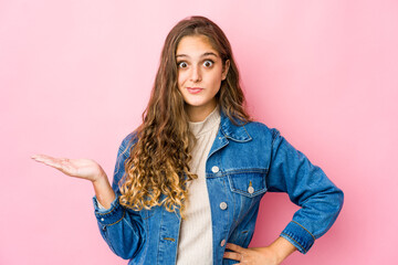 Young caucasian woman showing a copy space on a palm and holding another hand on waist.